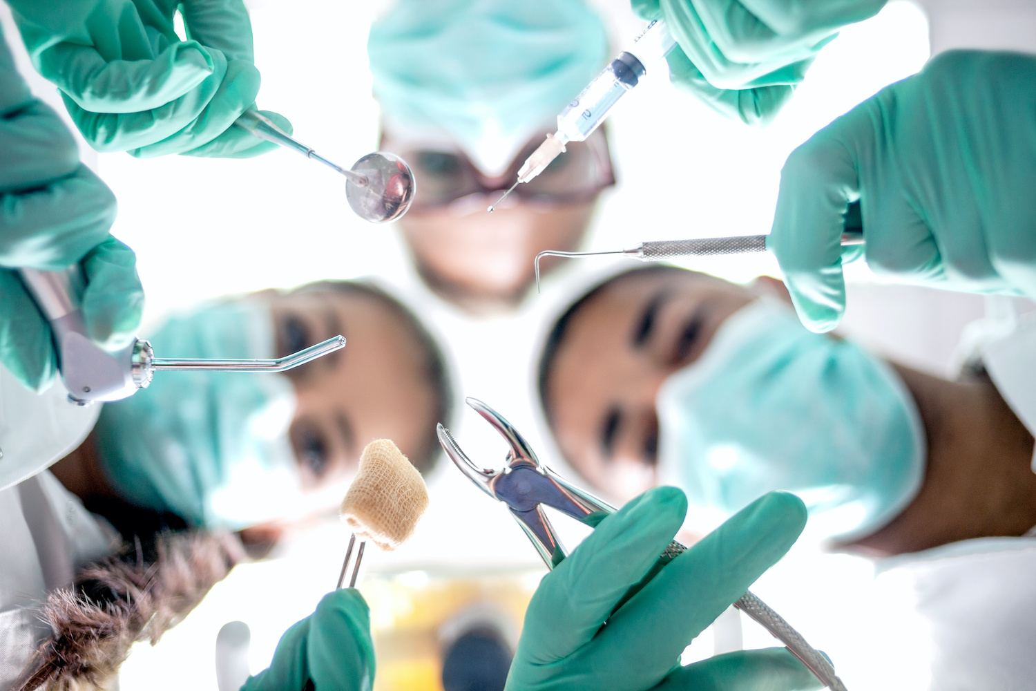 Looking up into the masked faces of several dentists performing oral surgery