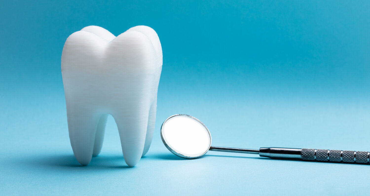 A white tooth next to a dental mirror on a blue background