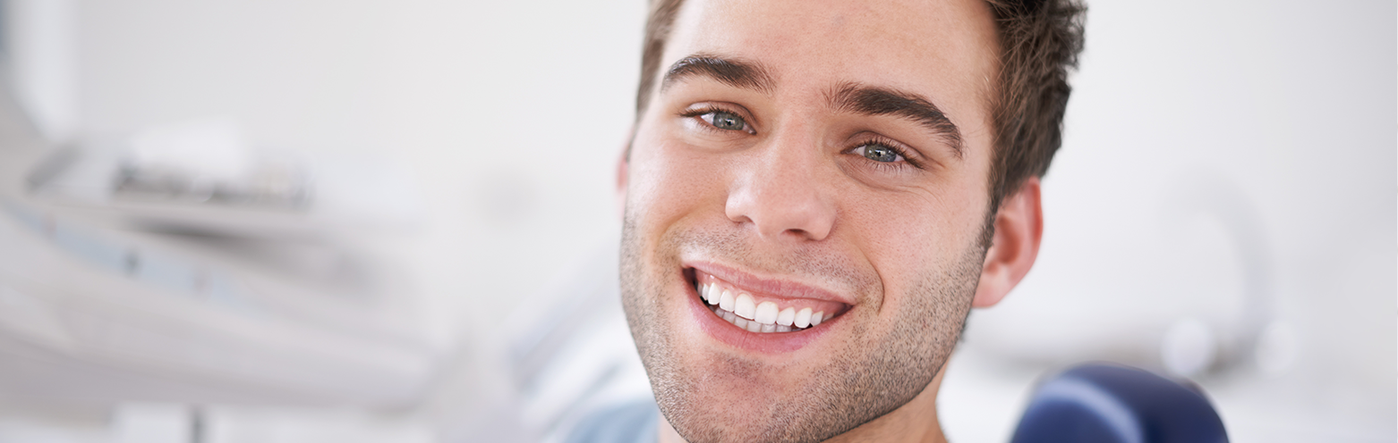 man smiling while sitting in a dental chair