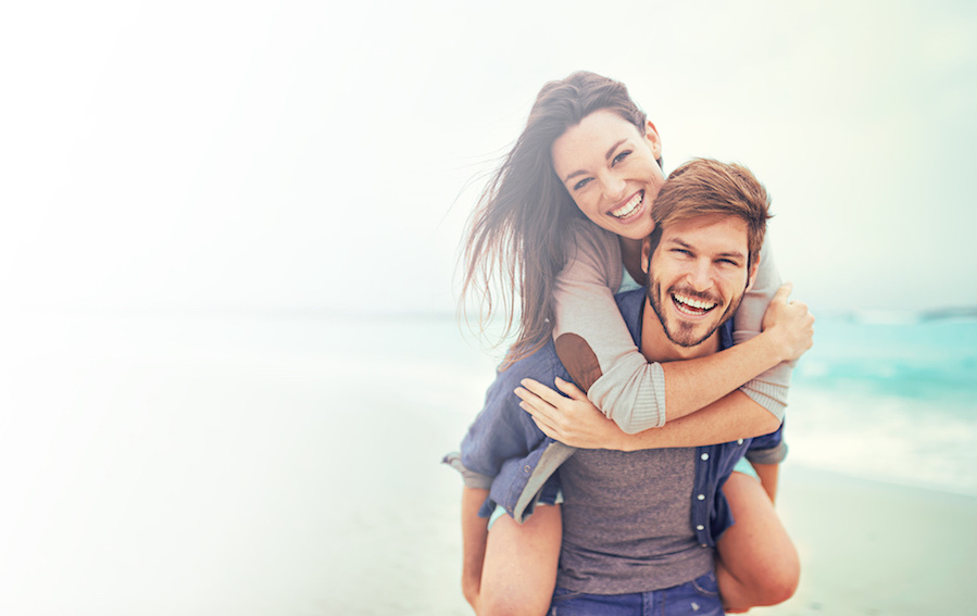 Photograph of smiling couple on the beach, restorative dentistry, benefits