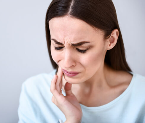 woman holding her jaw in pain