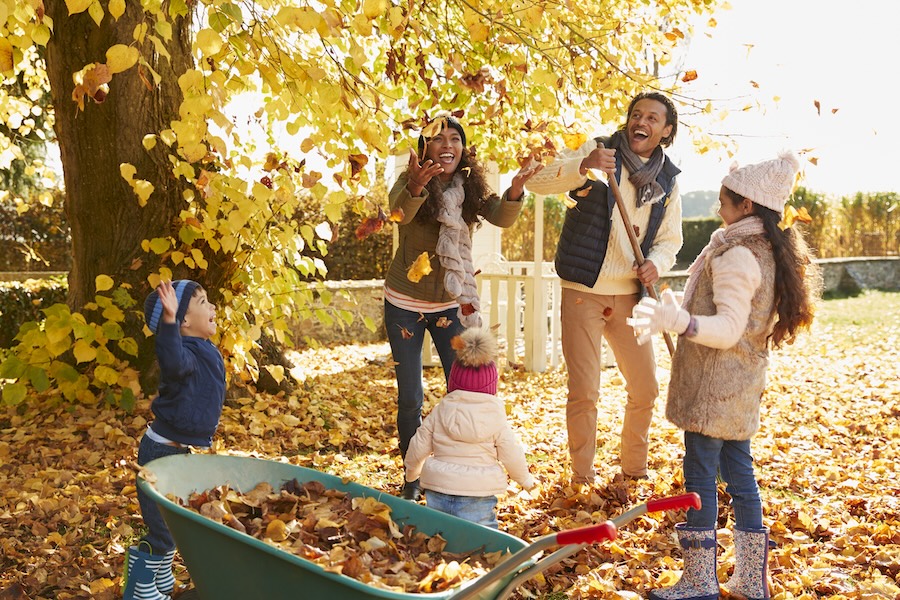 family playing in leaves before fall dental care